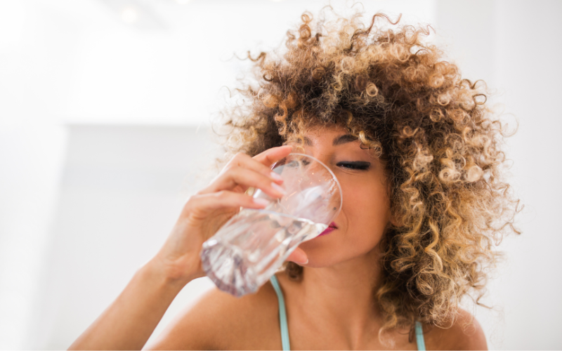 woman with curly hair drinking water