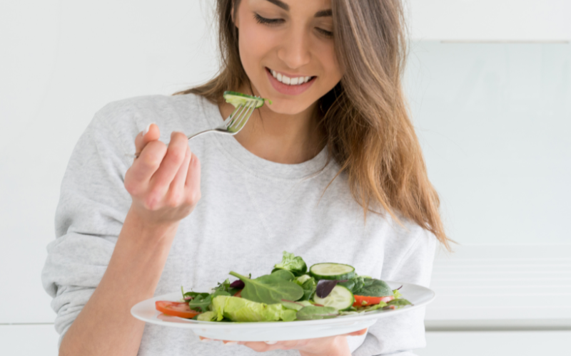 white woman eating healthy salad from white plate