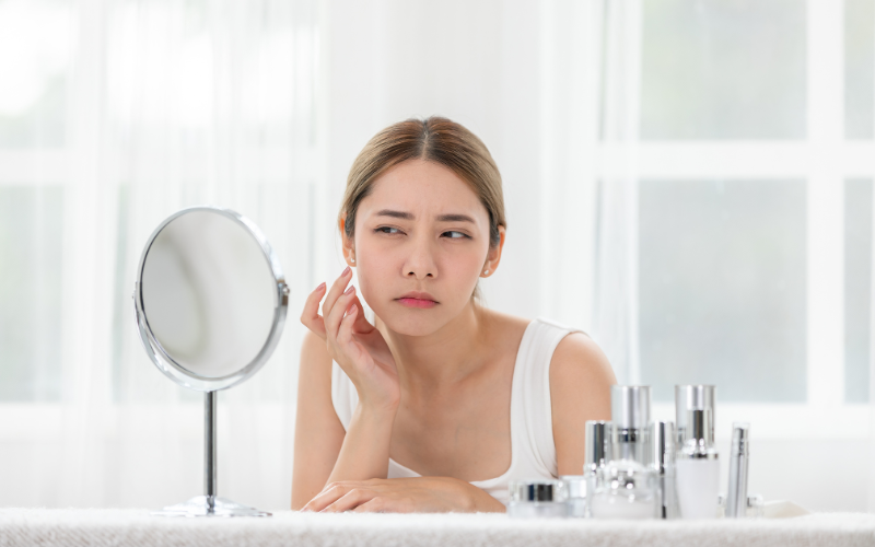 white woman with white background and white dress looking in the portable mirror