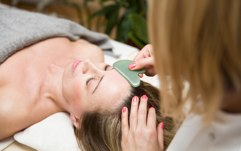 girl applying Gua Sha on face and forehead 