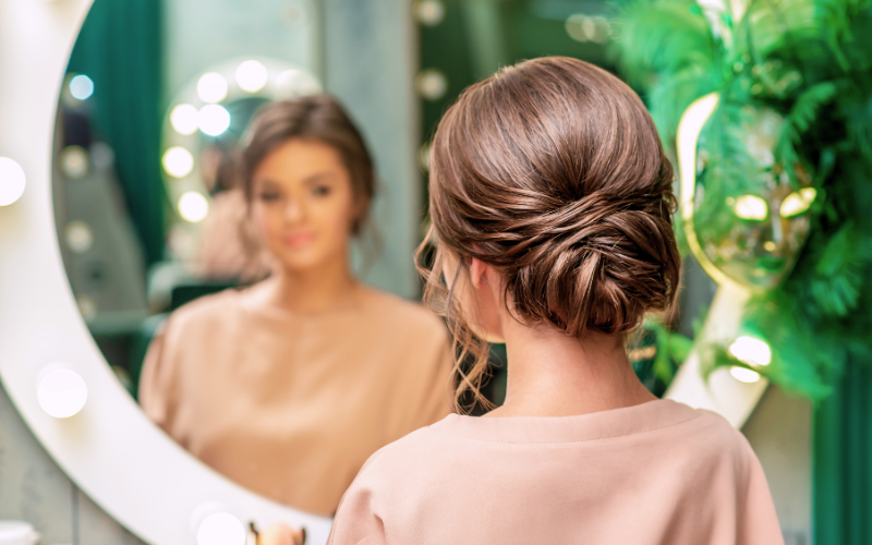 girl looking in mirror with hair bun hairstyle