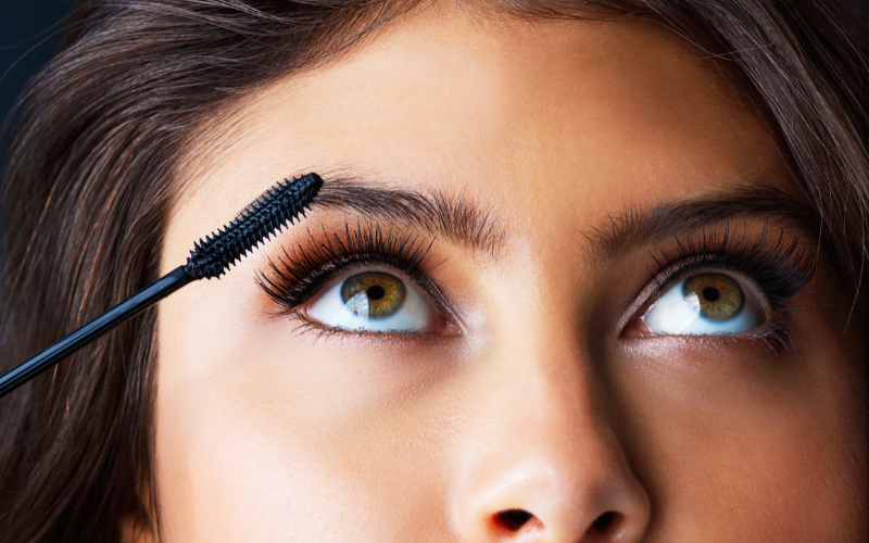 girl applying mascara on eye lashes 