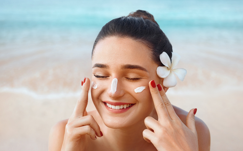 girl at beach applying Sunscreen on face