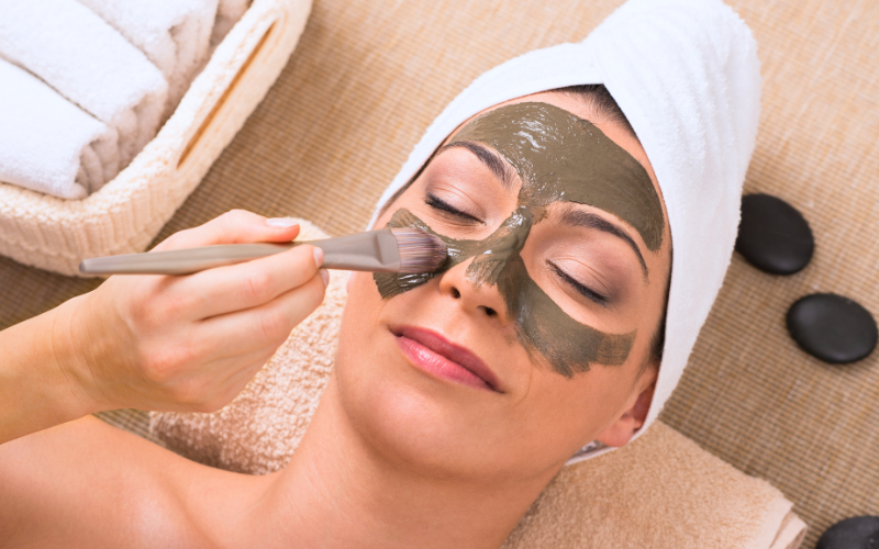 girl applying clay mask in face