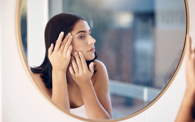 girl looking checking her face in mirror