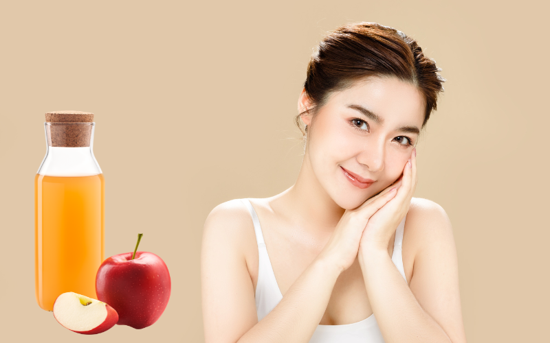 smiling woman looking in camera with hands on one side of face and apple cider vinegar placed on left